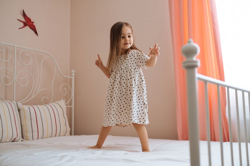 Girl jumping on the bed enjoying air quality.