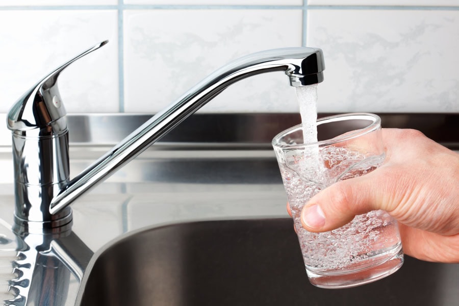 Hand holding a glass of water poured from the kitchen plumbing system.